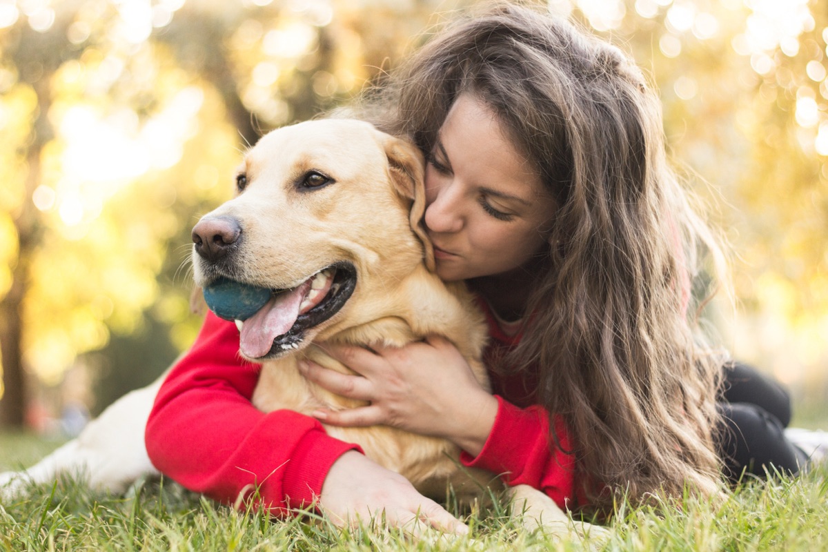 Pet owner hugging her golden retriever outdoors